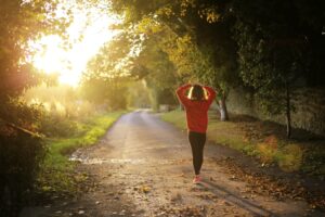 A person walking along a sunlit path, symbolizing gentle movement and physical activity.