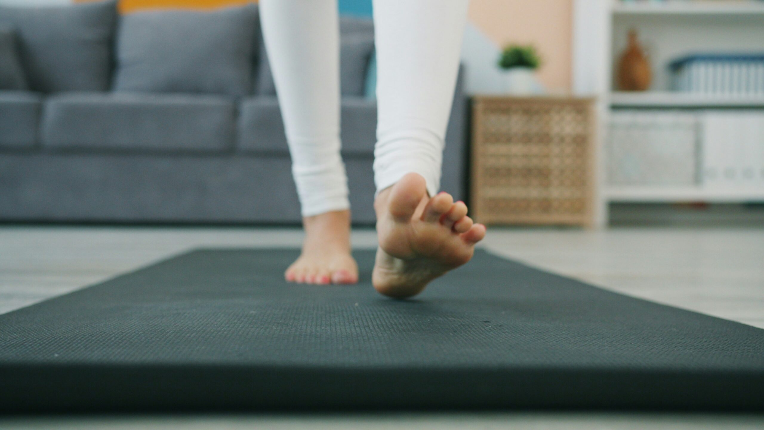 Bare feet walking on an exercise mat in a living room.